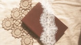 A delicate vintage diary with a shabby green cover resting on a lace tablecloth.