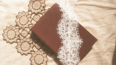 A delicate vintage diary with a shabby green cover resting on a lace tablecloth.