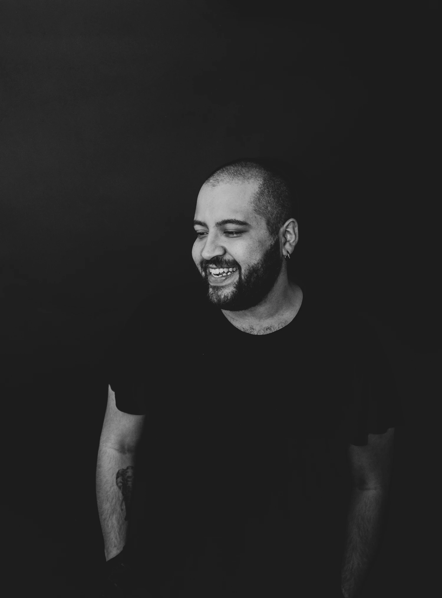 A man in a dark shirt photographed against a dark wall