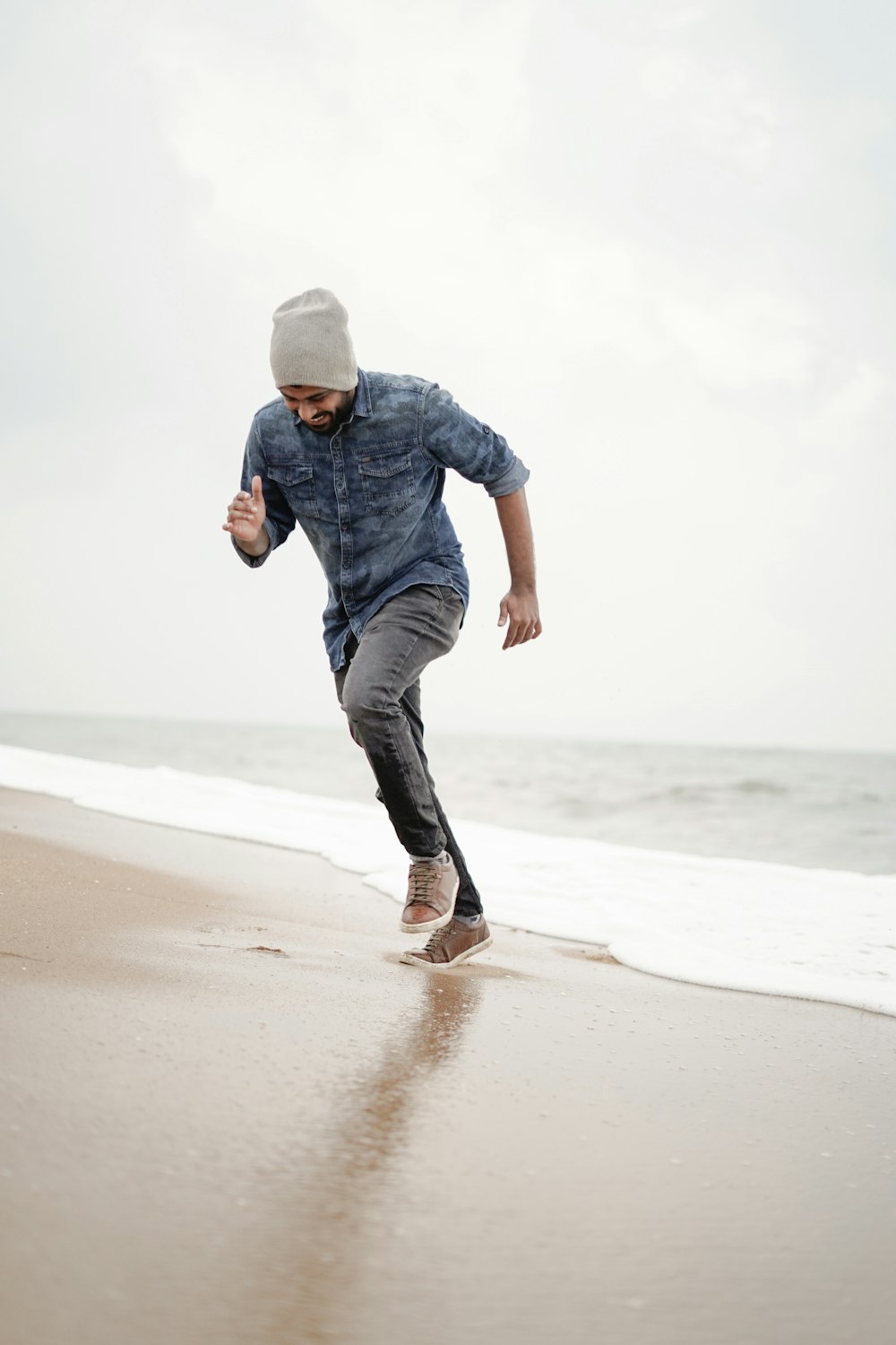 man in blue denim jacket and black pants walking on beach during daytime