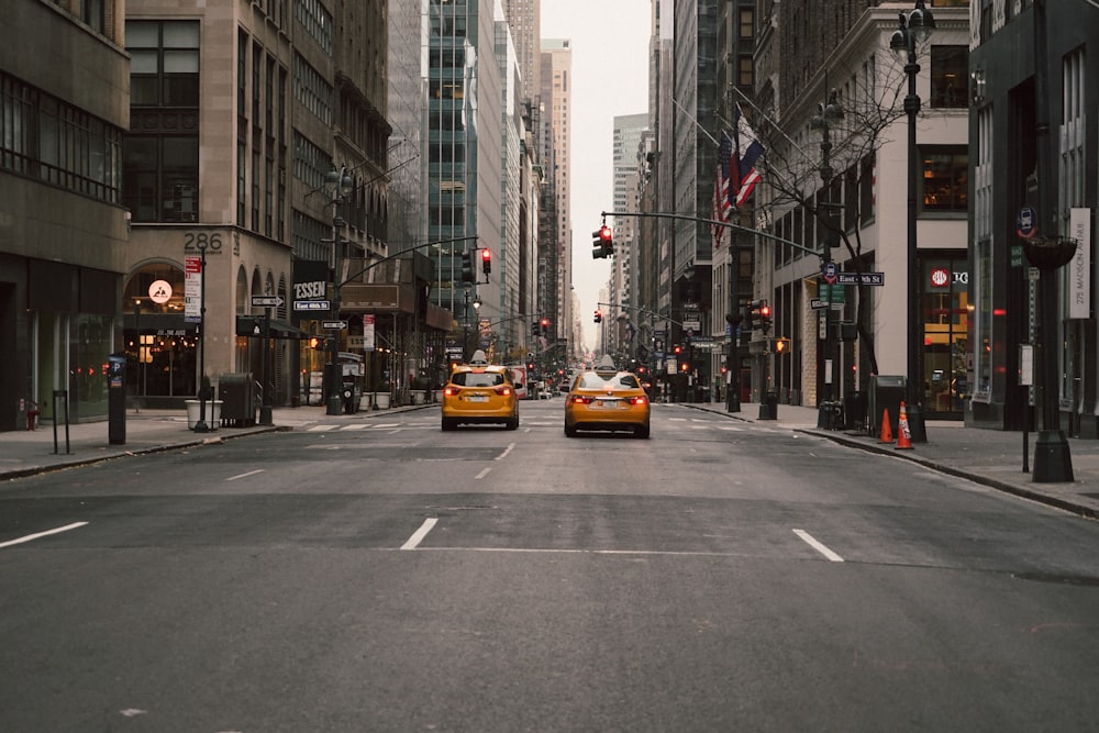 cars on road in between high rise buildings during daytime