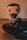 A pop culture figurine with a stylized design stands next to a video game controller on a wooden surface. The figurine has a cute, cartoonish appearance with an oversized head and minimal facial features. The game controller is a modern design with colorful buttons and analog sticks.