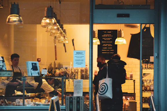 A friendly Grab n Go staff member smiling behind the deli counter with fresh sandwiches and snacks displayed.