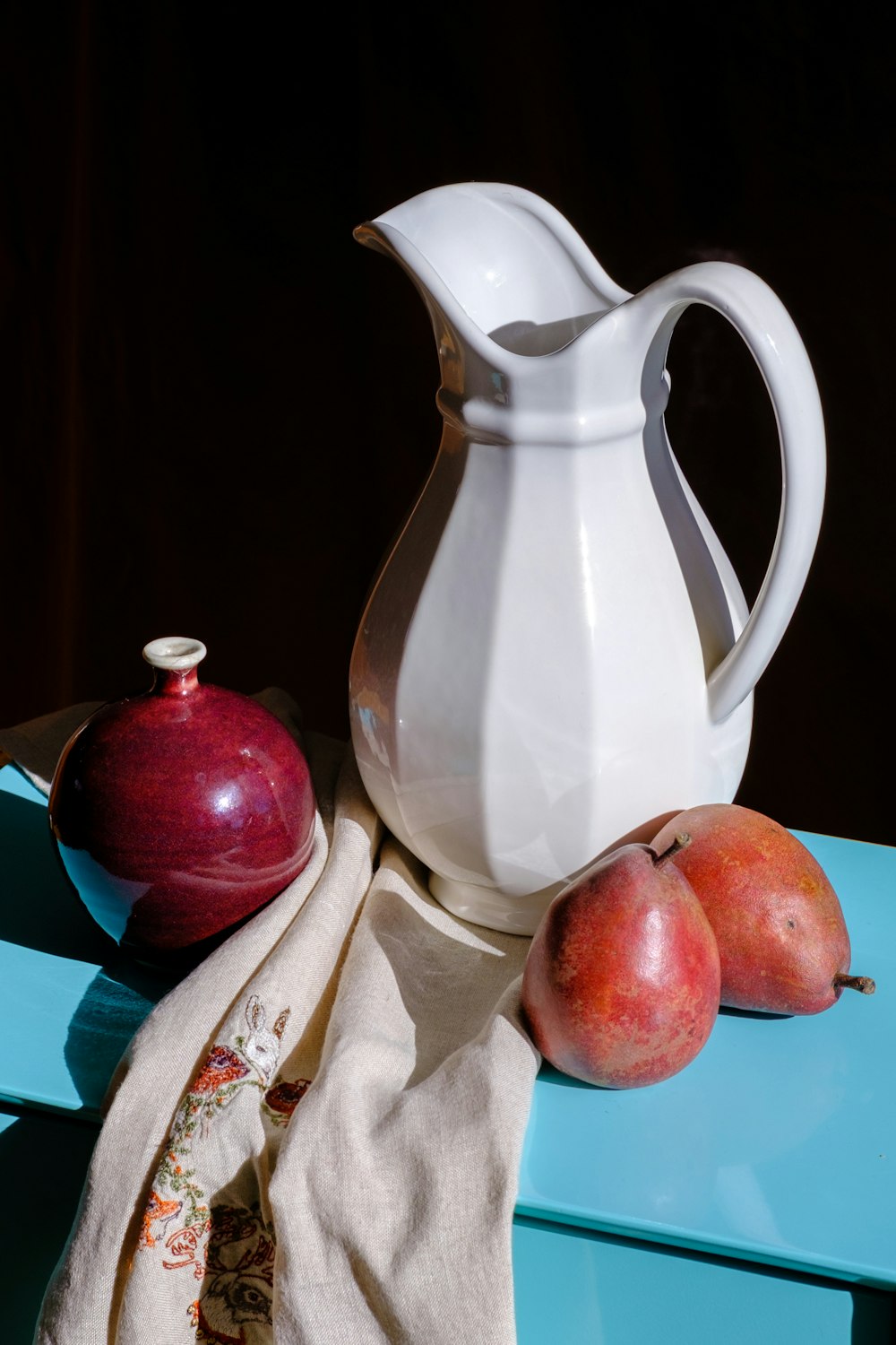 white ceramic pitcher beside red apple fruit