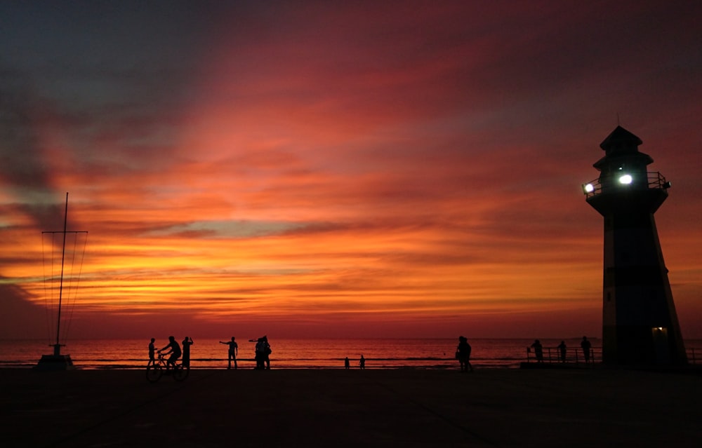 silhouette of people standing on beach during sunset