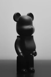 Minimalist collectible art toy with matte black finish, spotlighted against a deep grey backdrop.