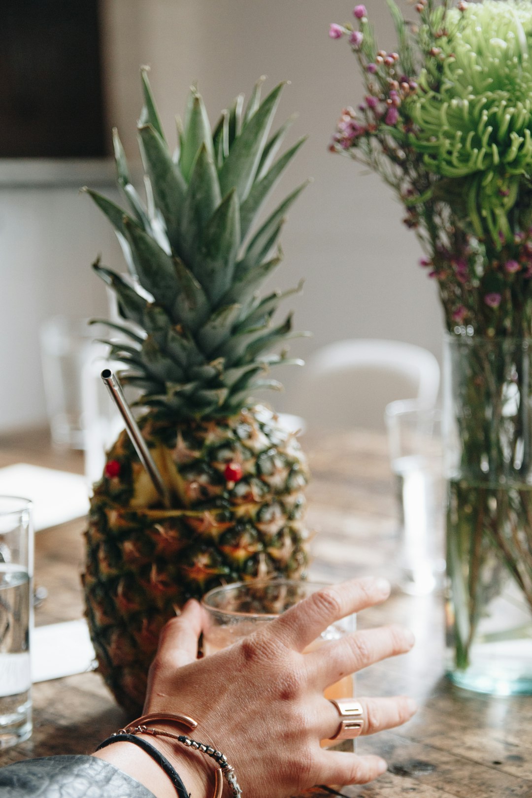 person holding pineapple fruit near clear drinking glass