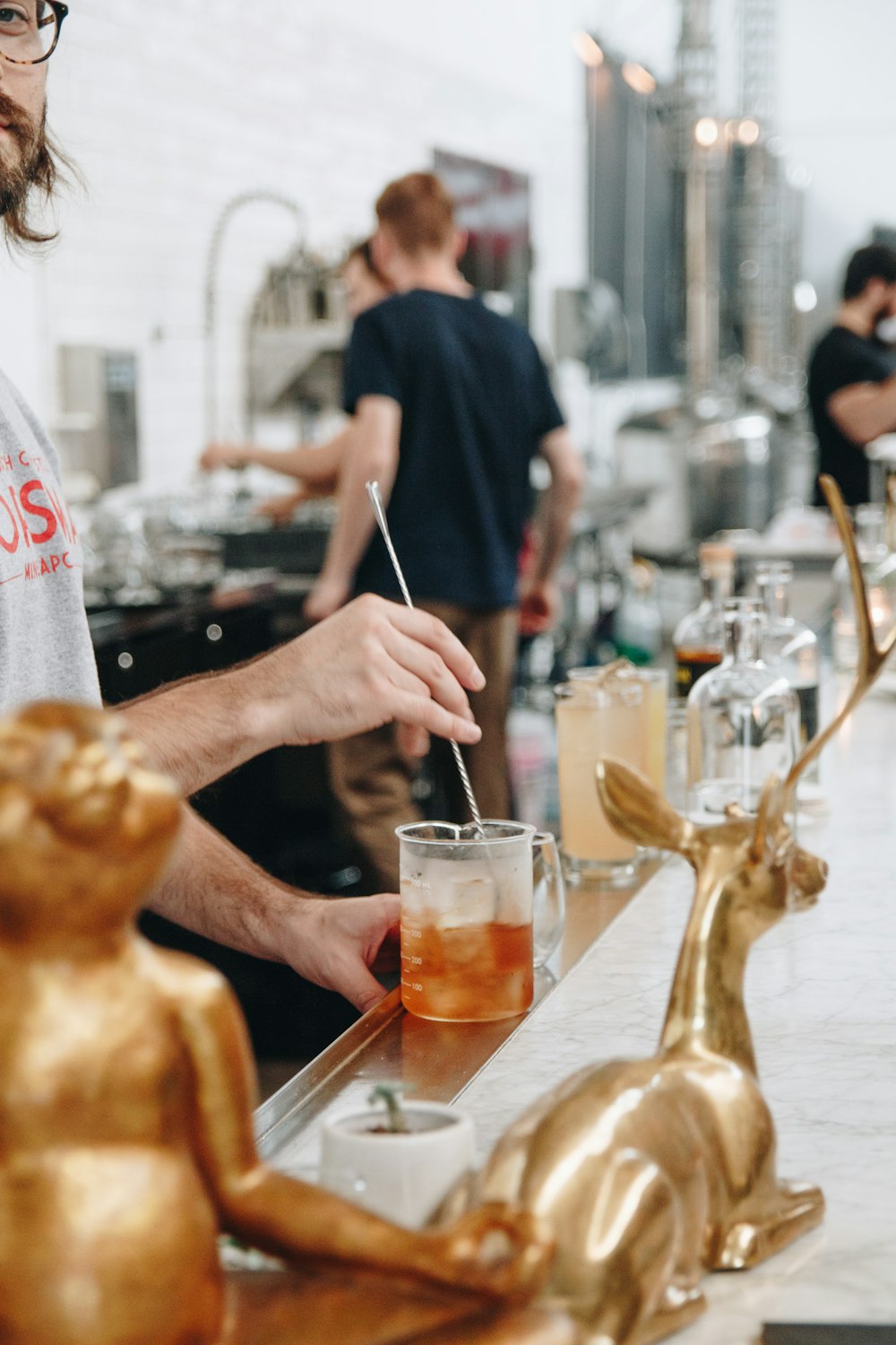 homme en t-shirt noir tenant une bouteille en verre transparent versant sur un verre à boire transparent