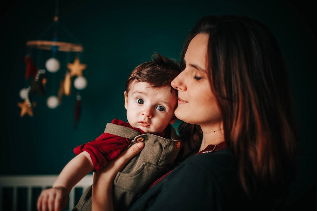 woman in black shirt carrying boy in red shirt