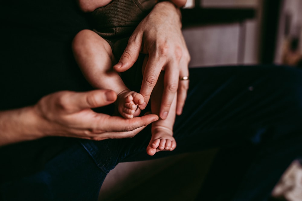 person in black pants holding babys feet
