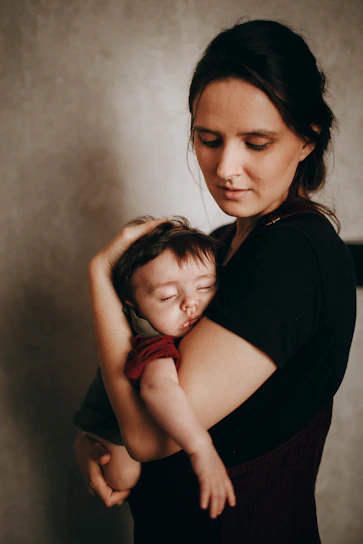 A warm, comforting illustration of a parent gently holding their baby, with soft pastel colors evoking calm and care.