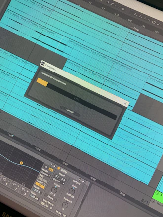 A digital audio workstation screen displaying a music arrangement with multiple tracks. The tracks are organized in horizontal lanes, filled with blue waveforms and labels. A dialog box in the center shows the process of freezing the arrangement with a progress bar partially filled. Various controls and panels, such as equalizers and input/output settings, are visible at the bottom.