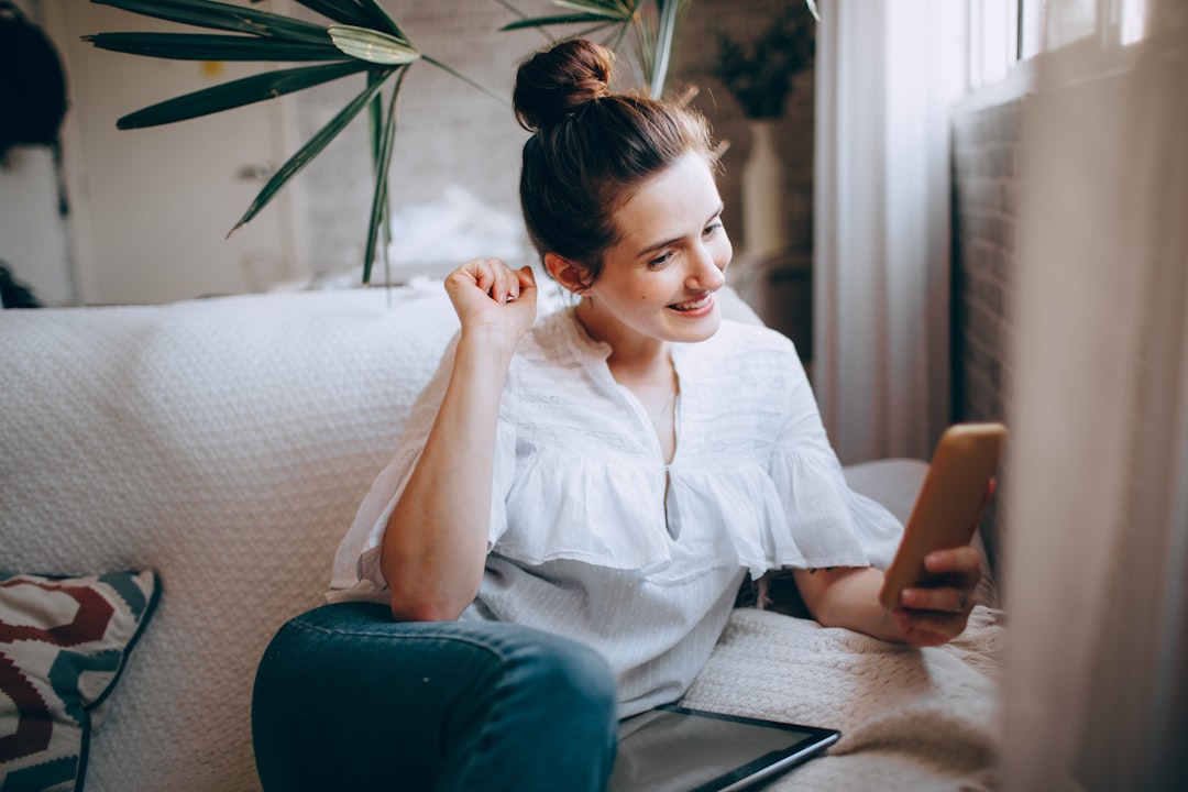 woman in white button up shirt and blue denim jeans sitting on gray couch