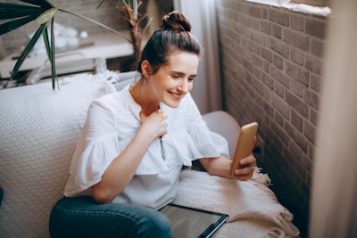 Woman smiling while working on her smartphone at home, feeling motivated.