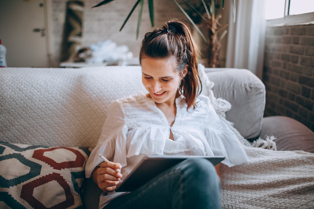 woman in white button up shirt and blue denim jeans sitting on white couch