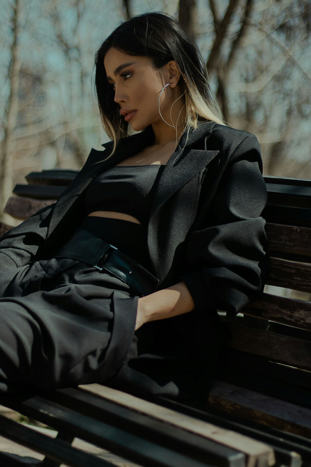 갈색 나무 벤치에 앉아 검은 코트를 입은 여자