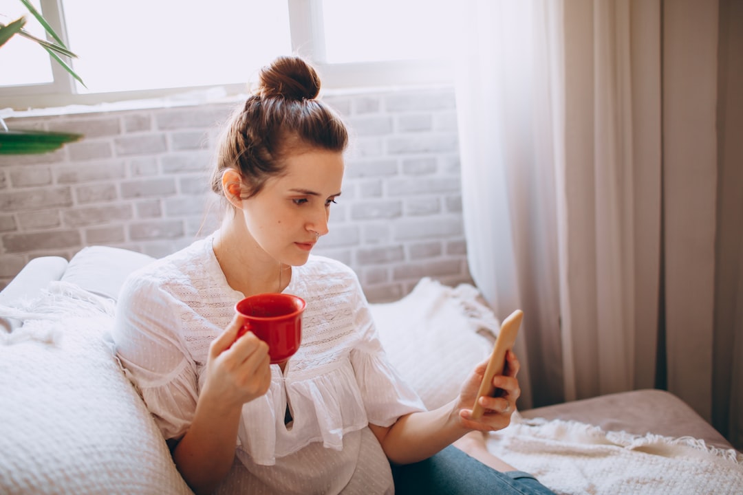 woman in white long sleeve shirt holding red ceramic mug