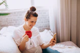 Young woman smiling while checking tasks on her smartphone in a cozy room.