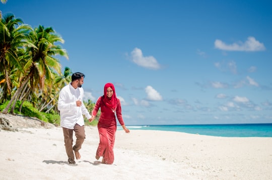 man in red robe walking on beach during daytime in Fuvahmulah Maldives