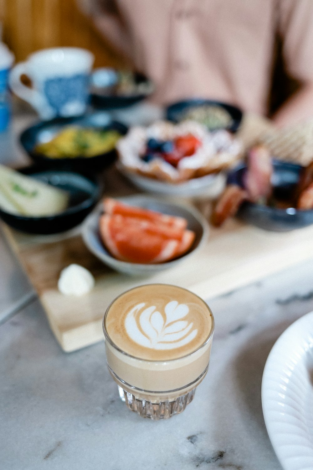 person pouring white cream on white ceramic cup