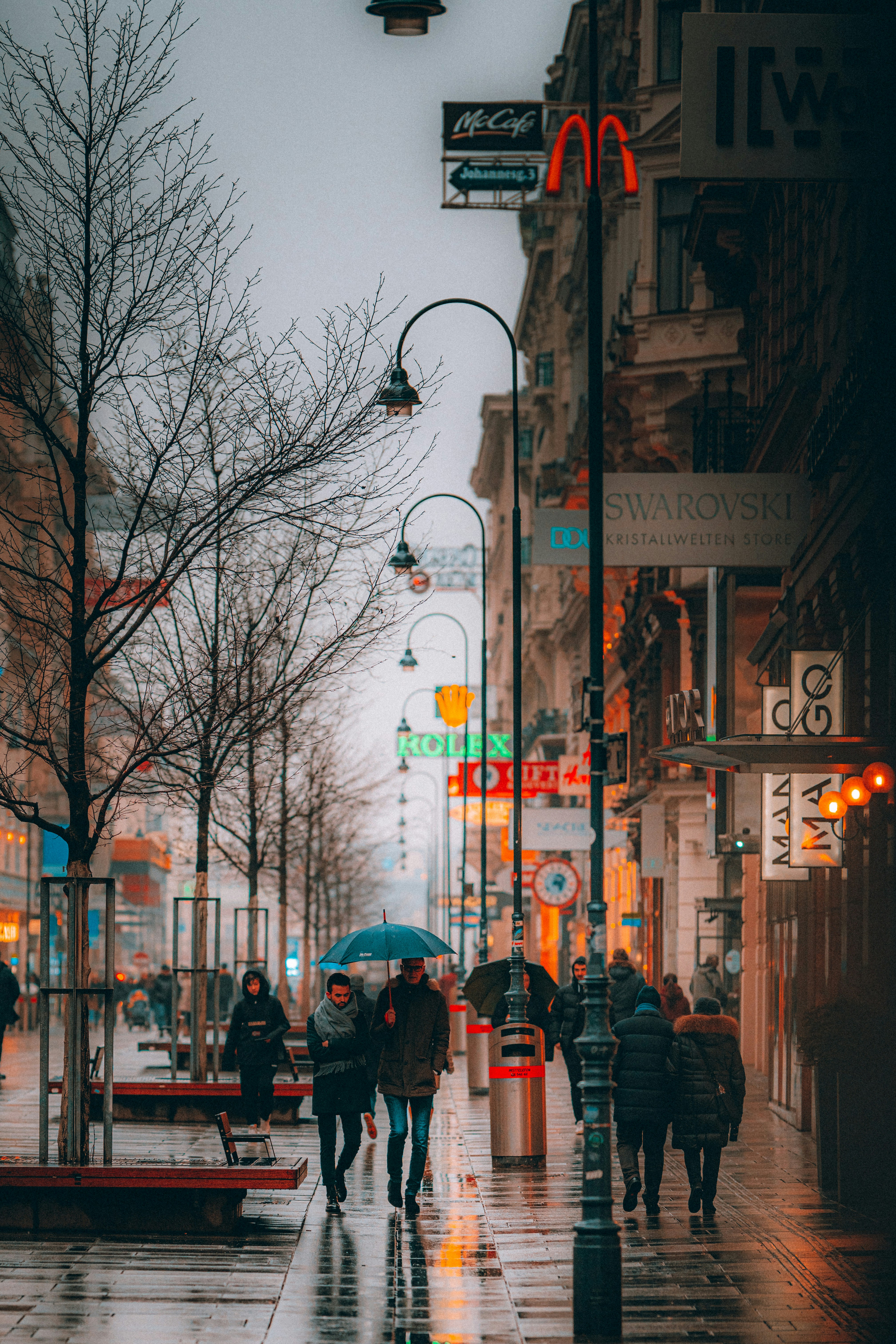 Menschen, die tagsüber mit Regenschirm auf dem Bürgersteig spazieren gehen
