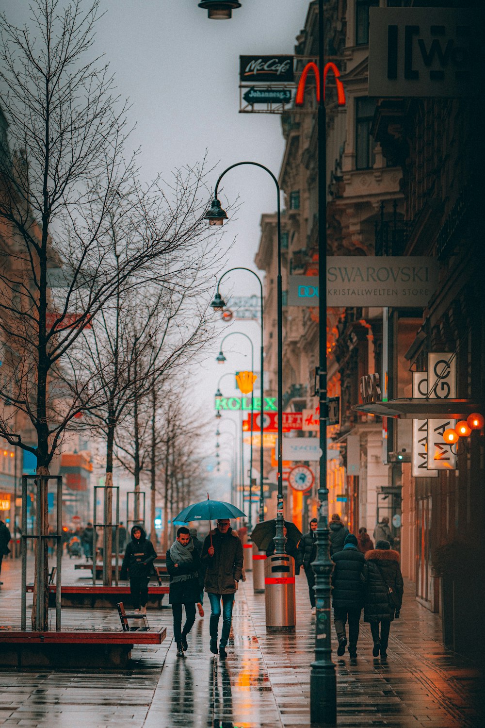 personnes marchant sur le trottoir avec un parapluie pendant la journée