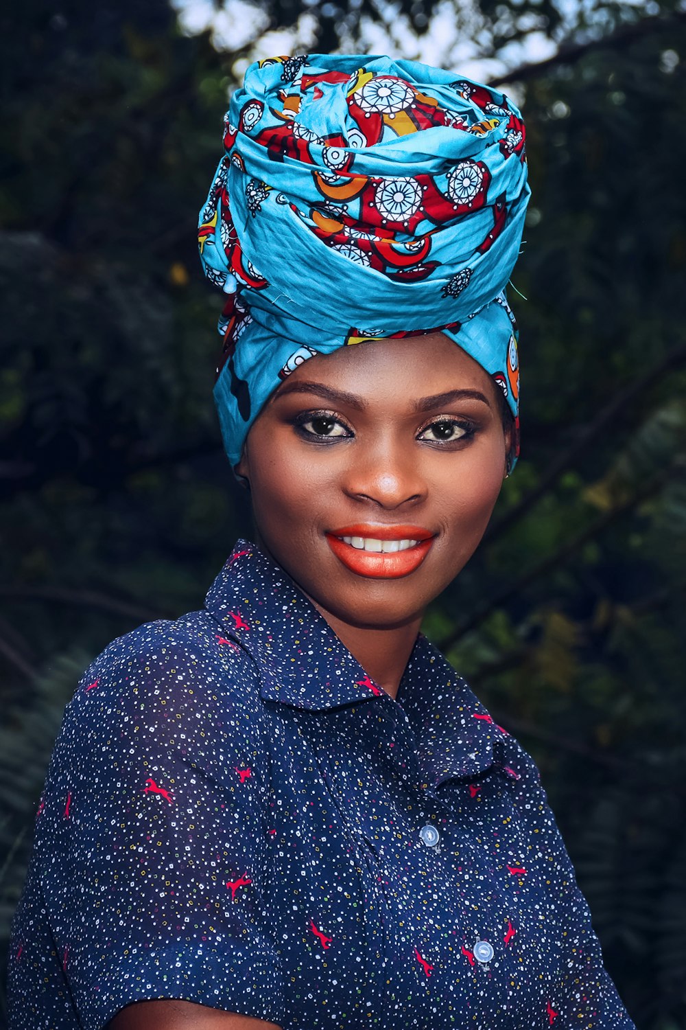 woman in black and white polka dot button up shirt with blue and green floral headdress