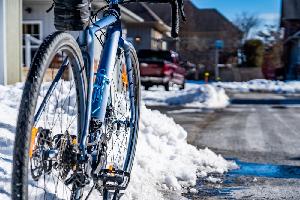 blue and black commuter bike on snow covered road during daytime
