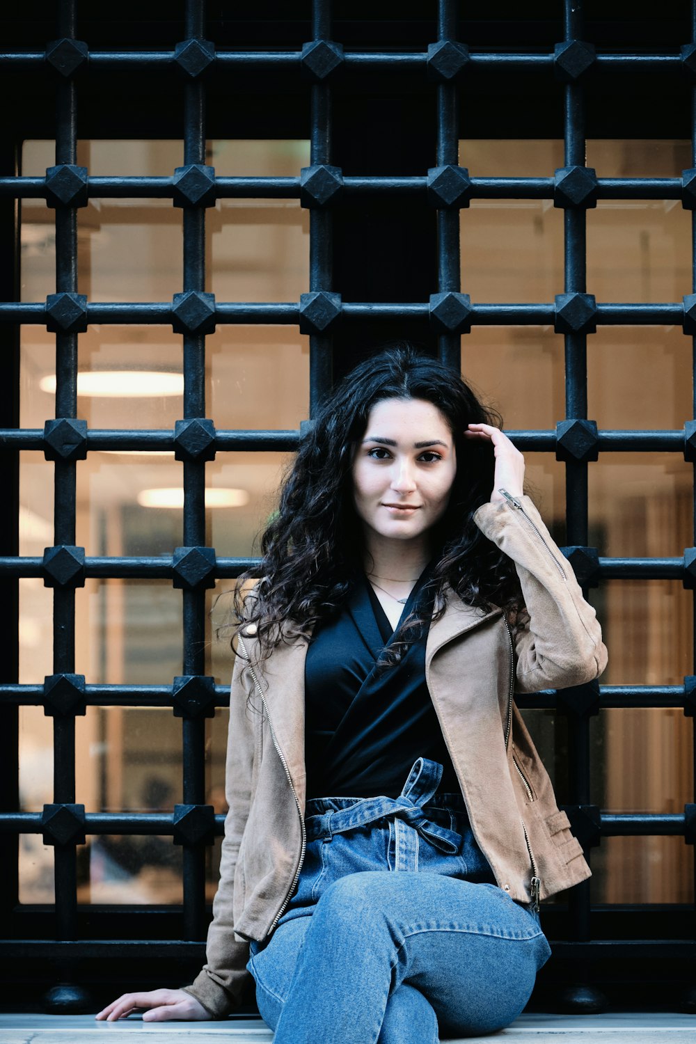 woman in brown coat standing beside brown metal fence