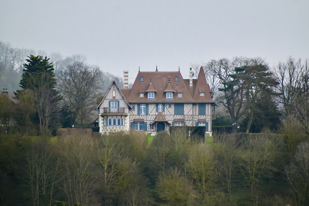 white and brown concrete house surrounded by green trees under white sky during daytime