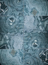 The image features a detailed close-up view of marble or stone tiles with intricate swirling patterns in shades of blue and gray. The tiles are arranged in a symmetrical pattern, creating a visually pleasing and consistent design.