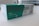 A box containing a COVID-19 antigen test kit, labeled 'Précisio Test', is placed on a white surface. The box is primarily green and white, with text in both English and Arabic. The image shows the product design and branding details.