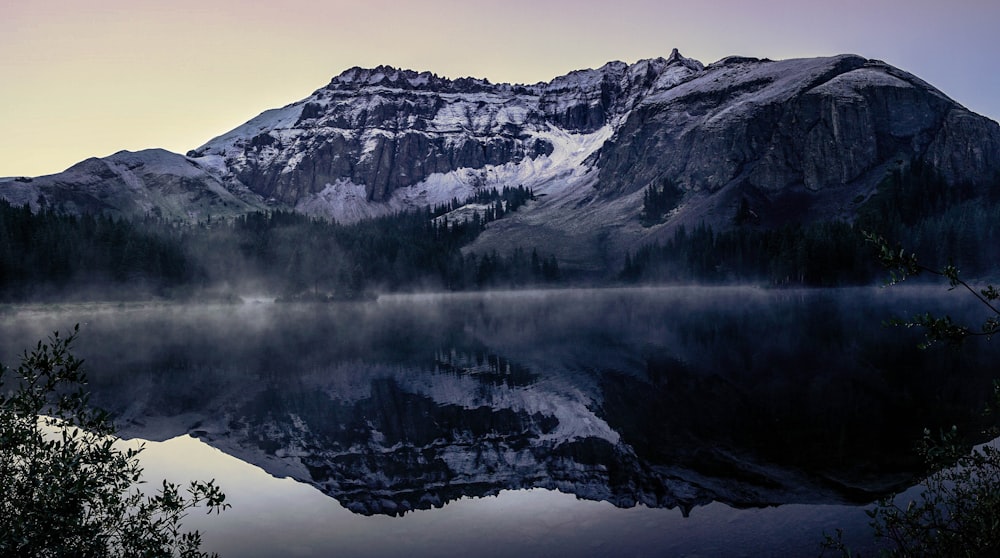 snow covered mountain near body of water during daytime