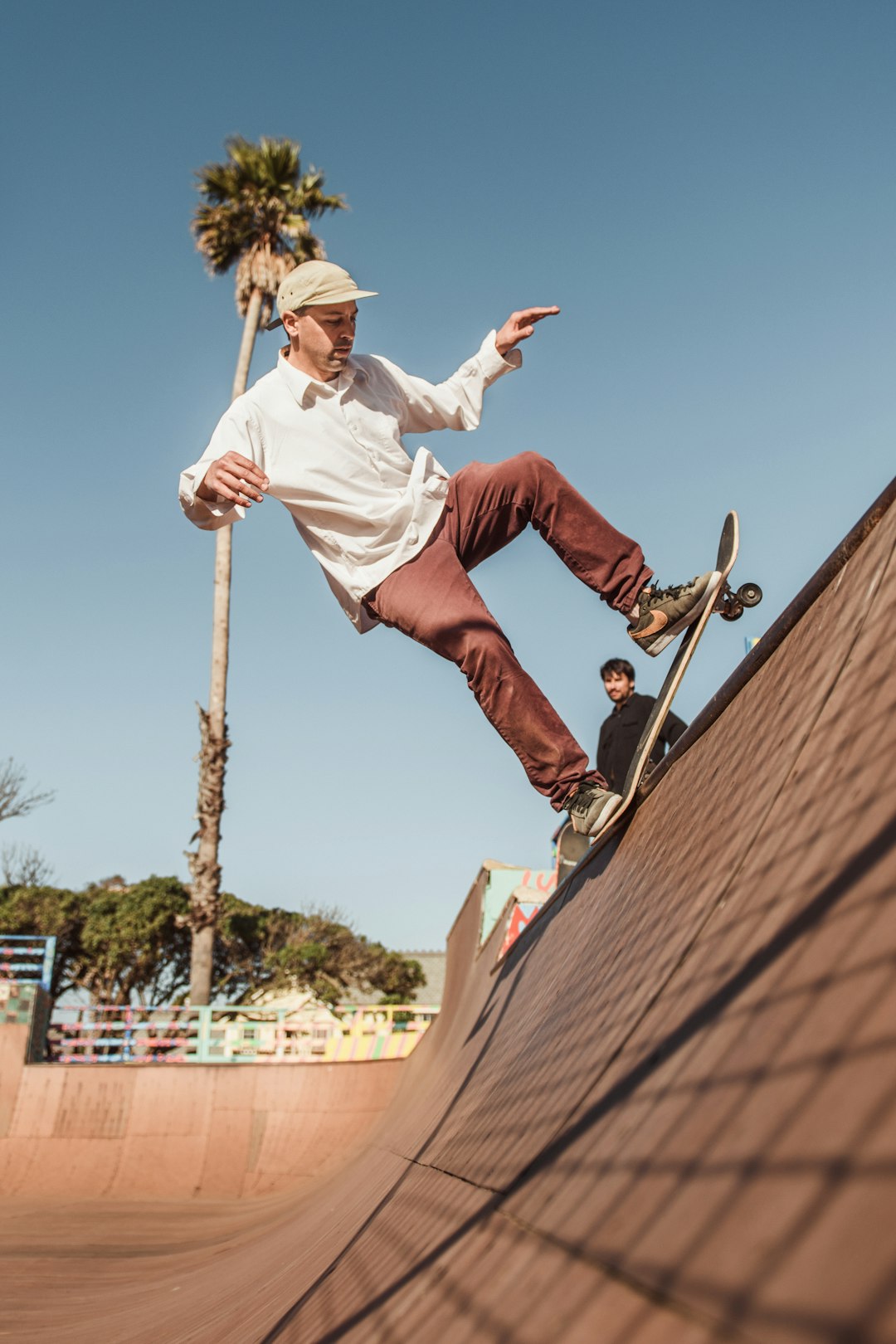 man in white shirt and red pants jumping on brown wooden pole during daytime