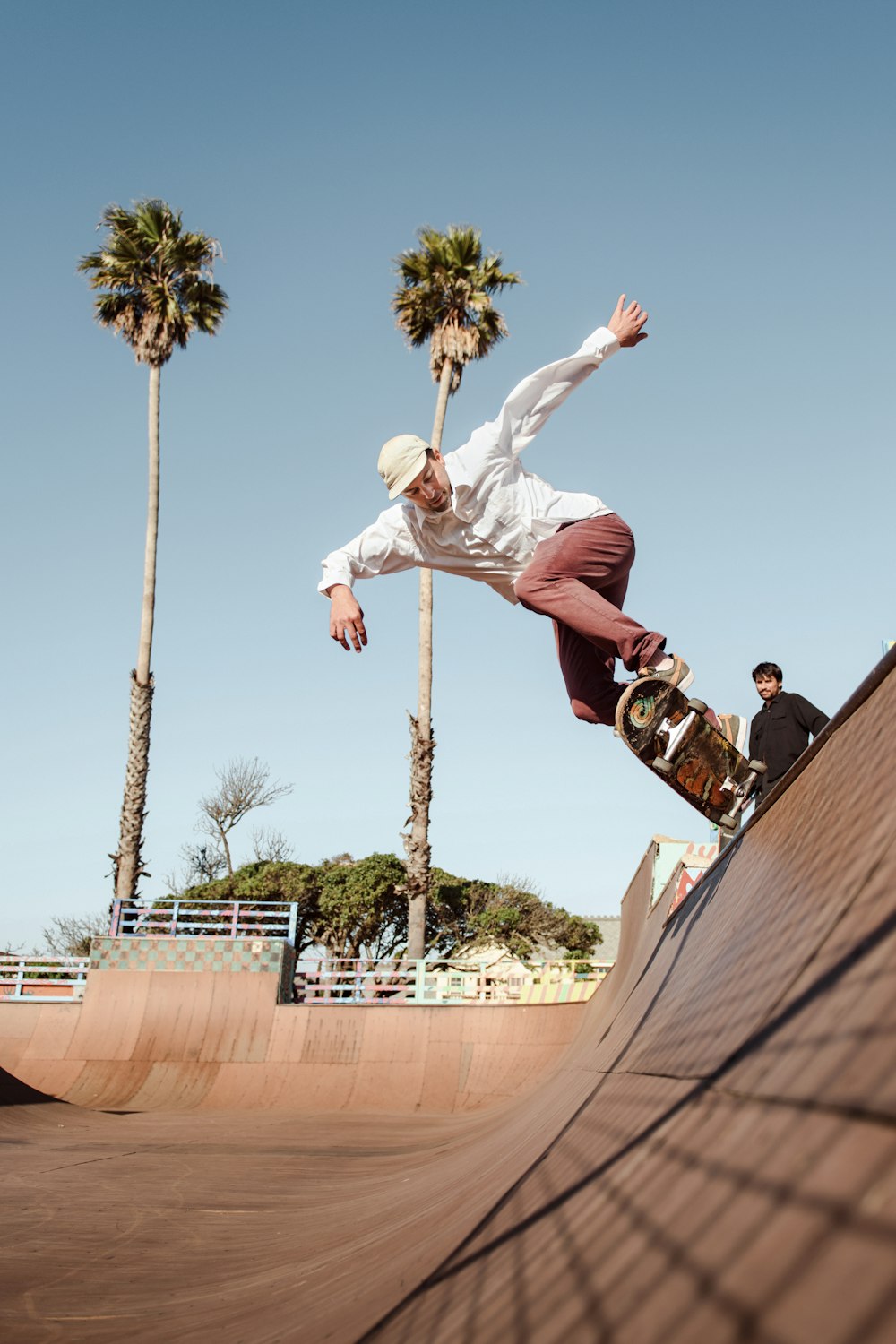 man in white shirt and brown pants jumping on brown concrete wall during daytime