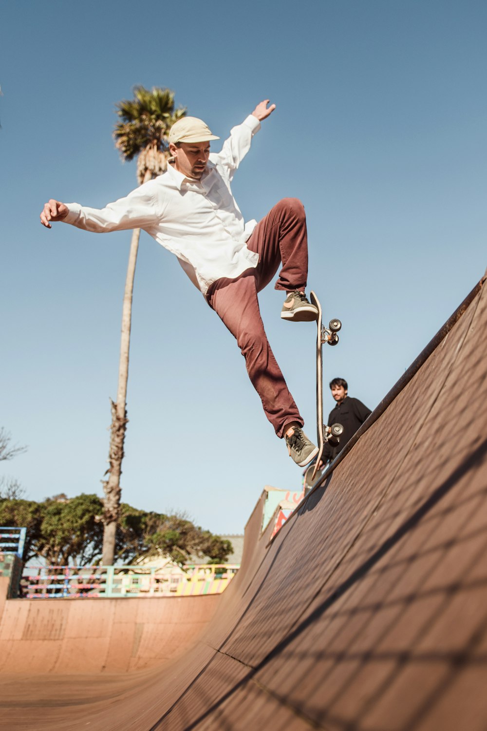 Hombre con camisa blanca y pantalones cortos rojos saltando en un poste de madera marrón durante el día