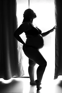 woman in black brassiere and panty standing beside curtain