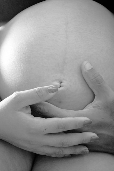 grayscale photo of pregnant belly and hands