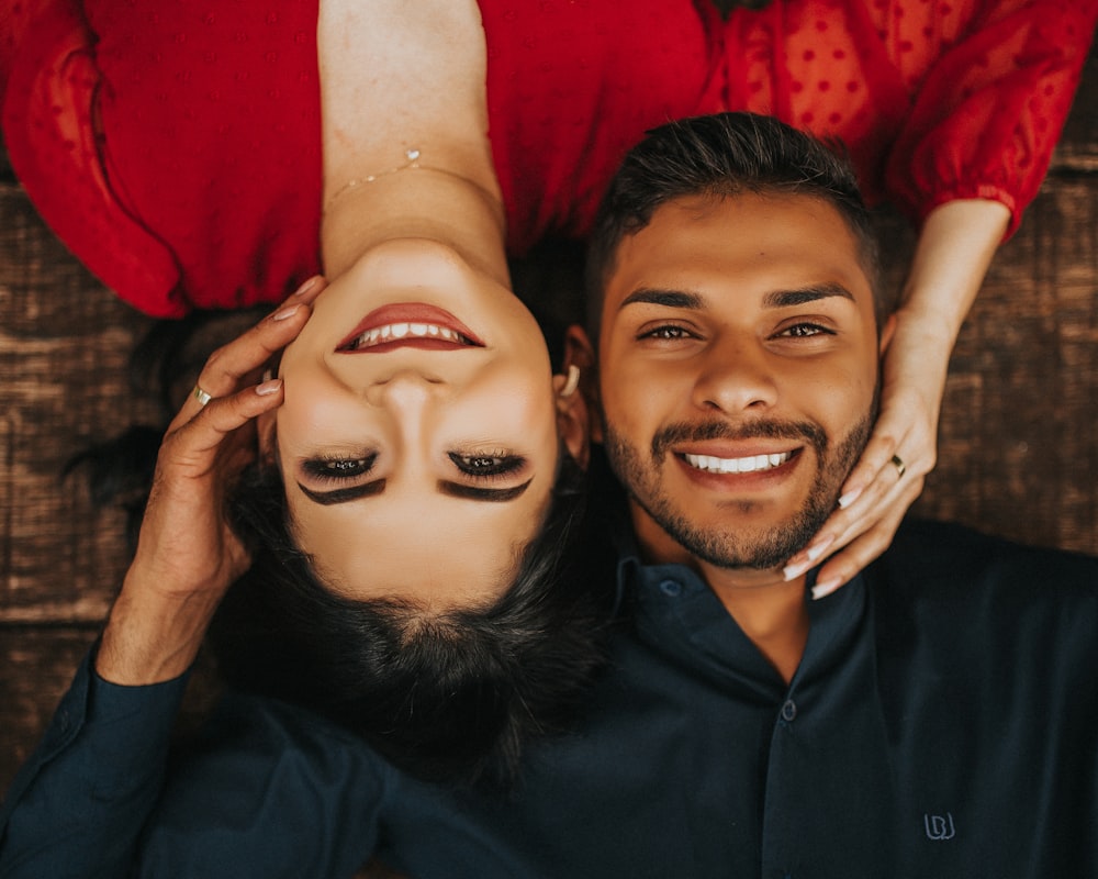 man in black polo shirt smiling beside woman in red lipstick