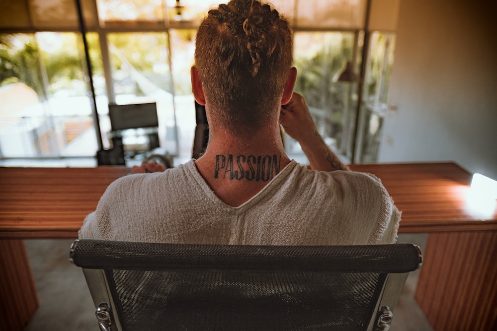 man in white crew neck shirt sitting on black chair