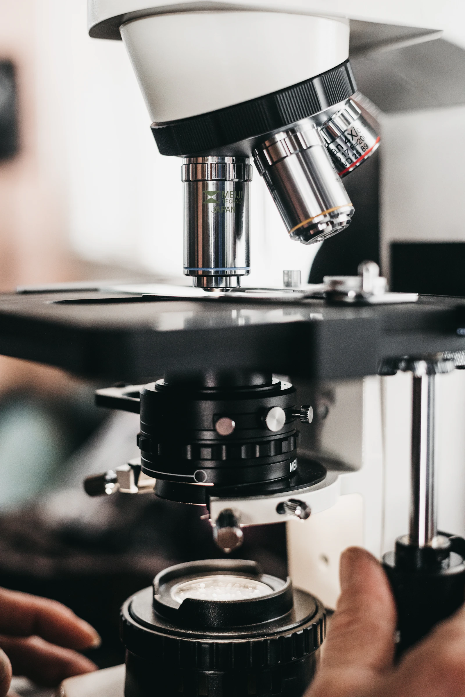 A person adjusting the focus of a laboratory microscope