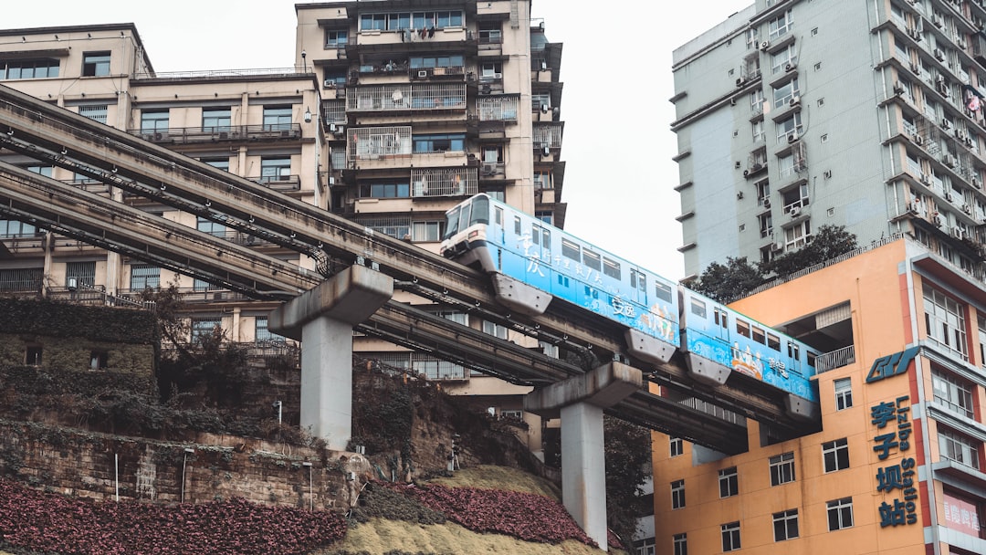 blue train on rail tracks near building during daytime