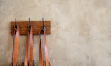 Stylish leather handbags hanging on rustic wooden hooks.