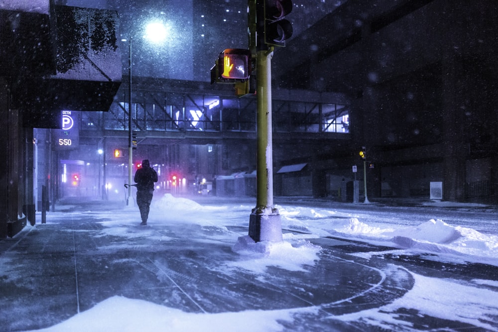 person in black jacket standing on snow covered road during night time