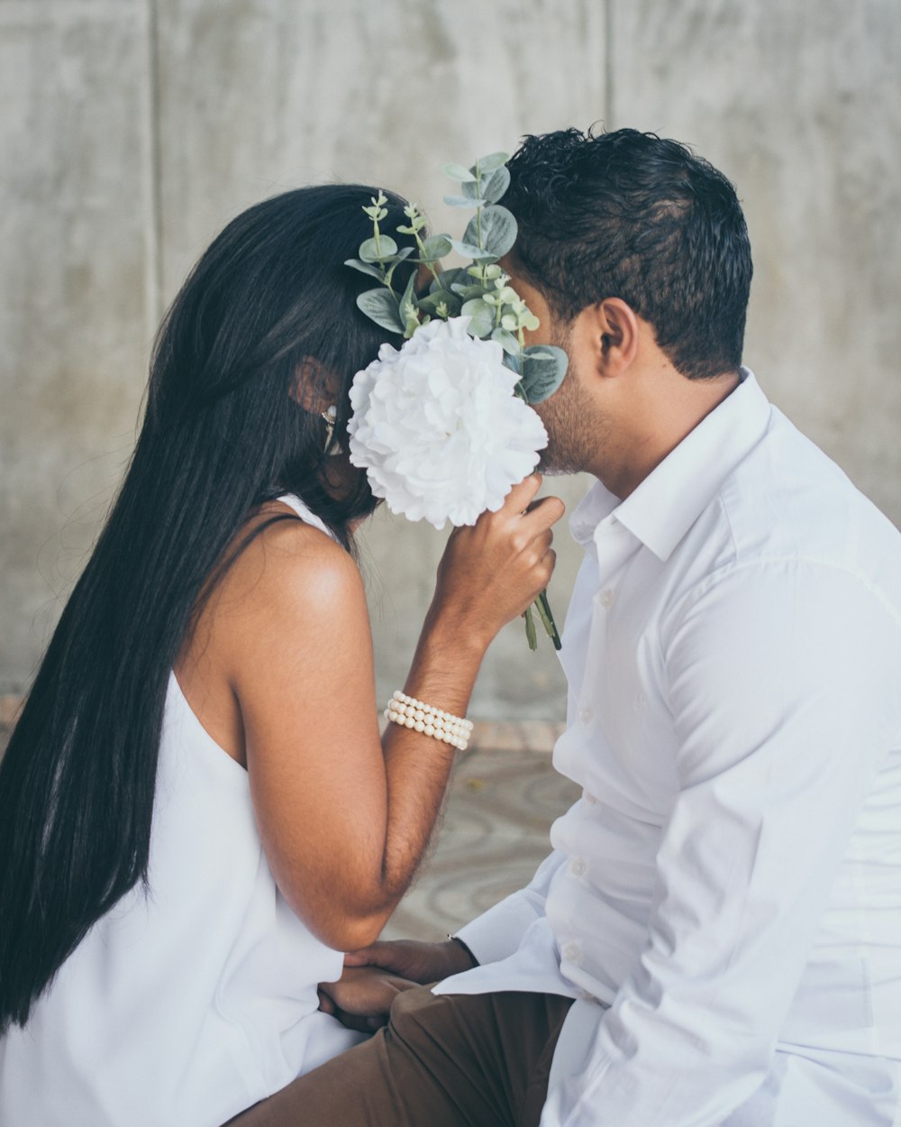 man in white suit kissing woman in white dress