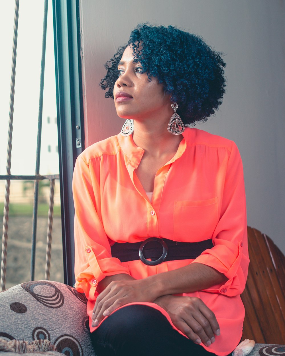 woman in orange button up shirt sitting on brown wooden chair