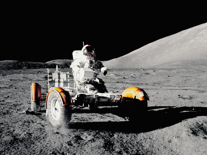 A robotic rover exploring rocky, reddish terrain under a dusty sky, evoking planetary surface exploration