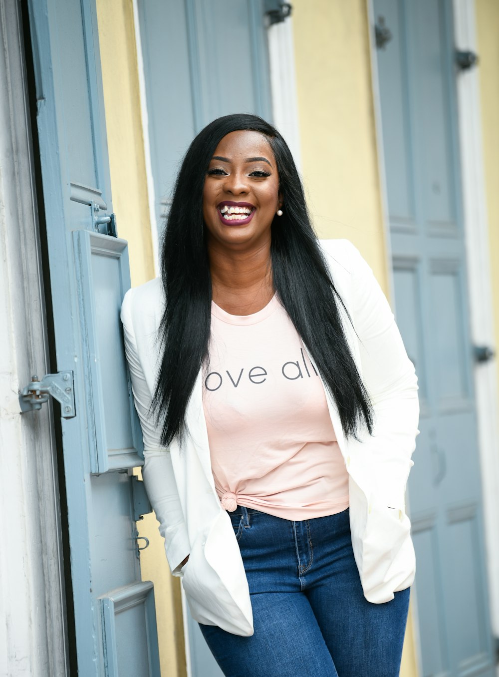 woman in white long sleeve shirt and blue denim jeans standing beside white wooden door during