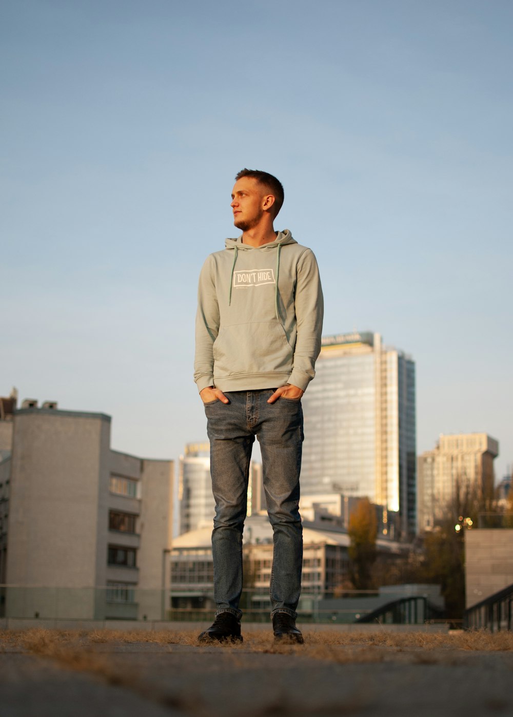 man in gray long sleeve shirt and blue denim jeans standing on gray concrete floor during