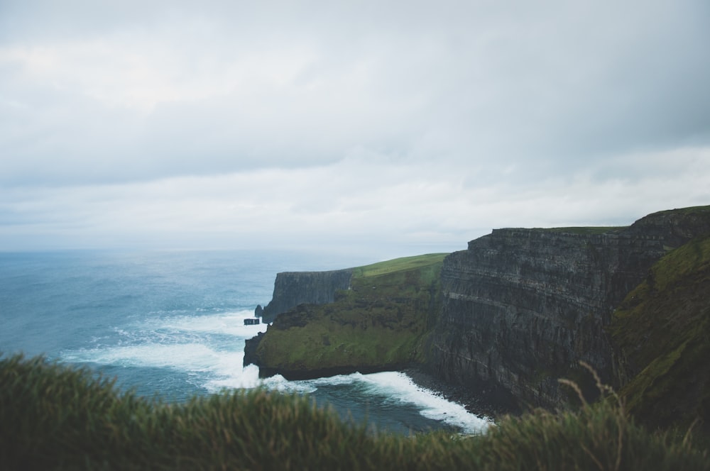 green and gray mountain beside body of water during daytime